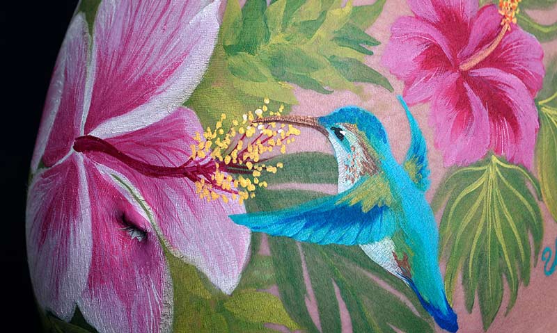 Babybauchbemalung mit Blumen und Kolibri, Detailaufnahme.