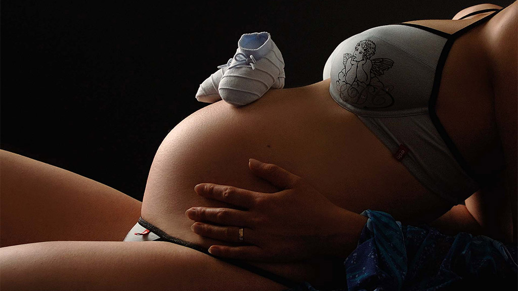 Babybauchshooting mit Babyschuhe auf dem Bauch
