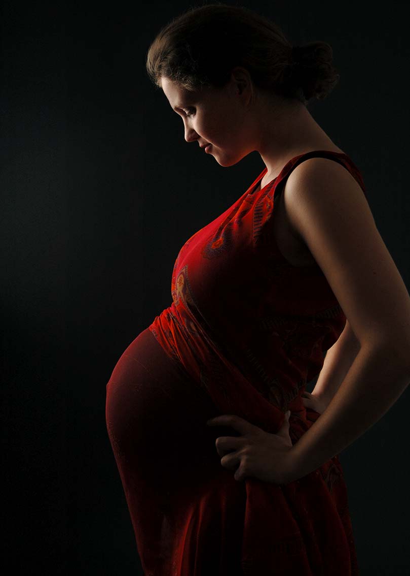 Schwangerschaftsfotografie - Schwangere in roten Kleid, Profilaufnahme, Halbportrait.